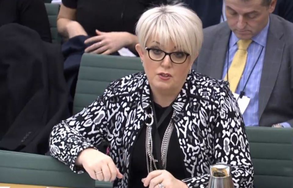 a woman wearing glasses and a leopard print jacket sits at a table