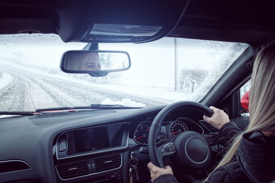 a woman is driving a car on a snowy road