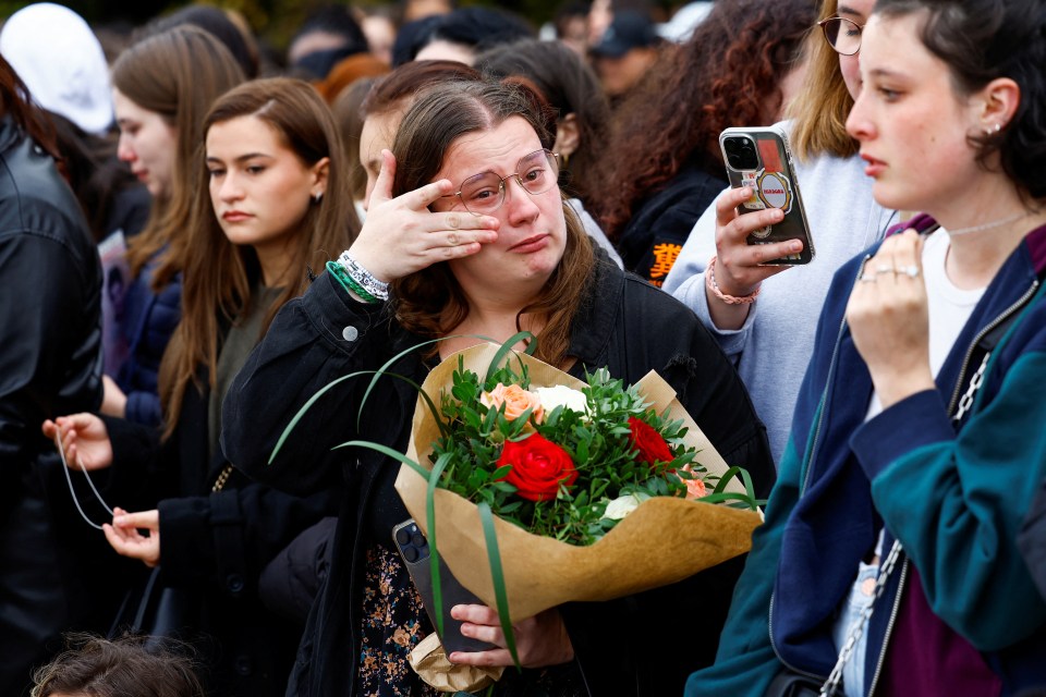 A woman wipes her tears at emotional scenes in France