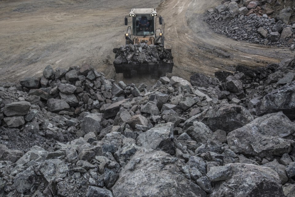 a bulldozer is driving through a pile of rocks