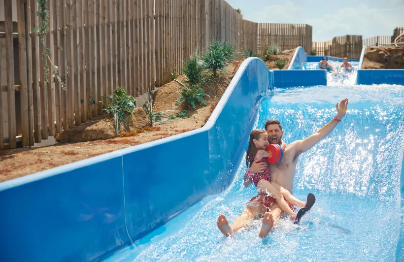 a man is holding a little girl on a water slide