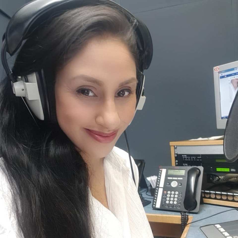 a woman wearing headphones stands in front of a microphone