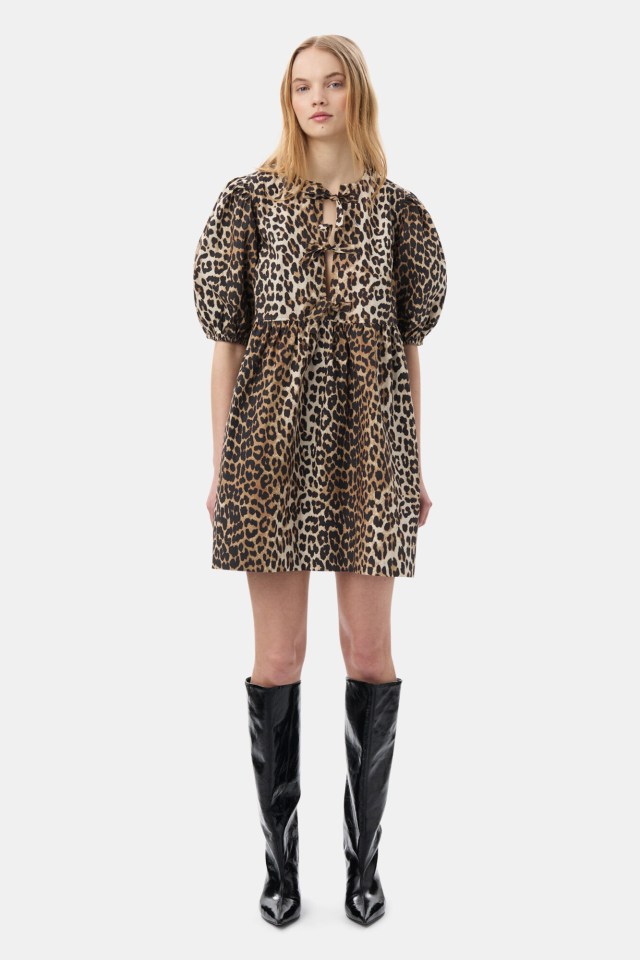 a woman wearing a leopard print dress and black boots