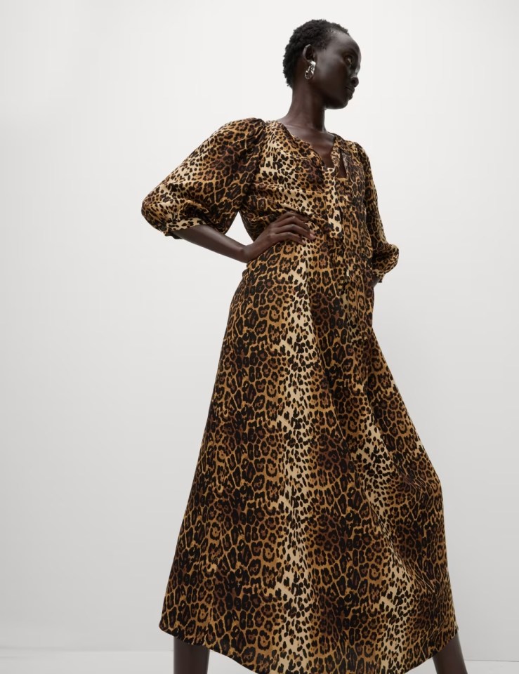 a woman in a leopard print dress sits on a chair