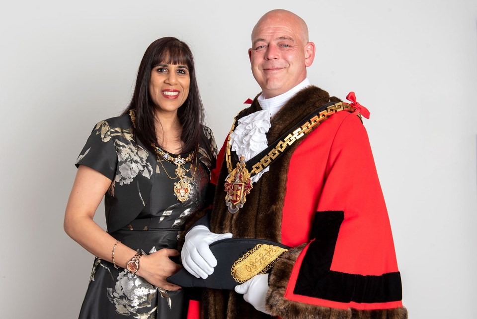 a man and a woman are posing for a picture and the man is wearing a robe that says mr. mayor