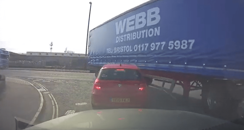 A BMW hatchback waiting at a junction is taken out by the trailer of a lorry turning into the bend