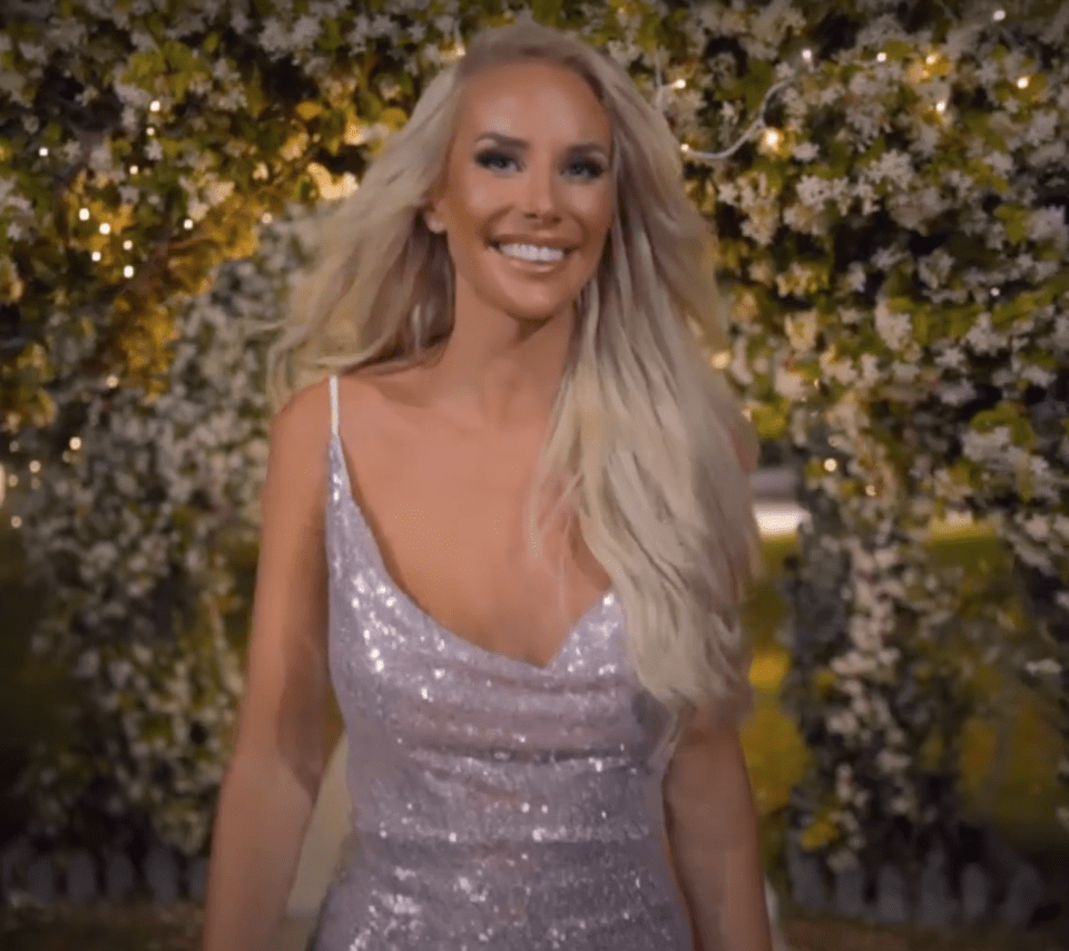 a woman in a sequined dress smiles in front of flowers