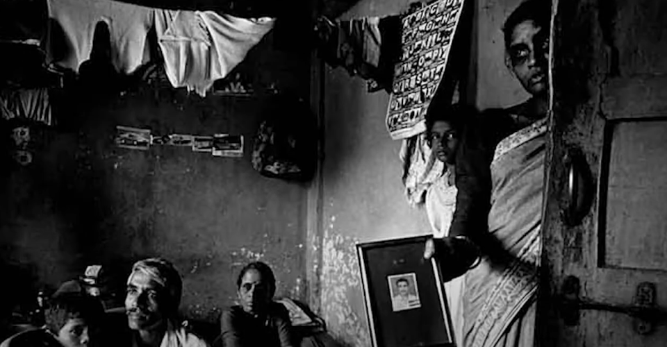 a group of people are sitting in a room holding a picture of a man .