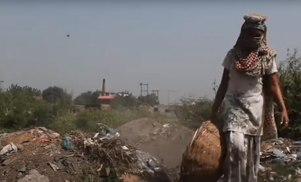 a woman wearing a mask is walking through a pile of trash