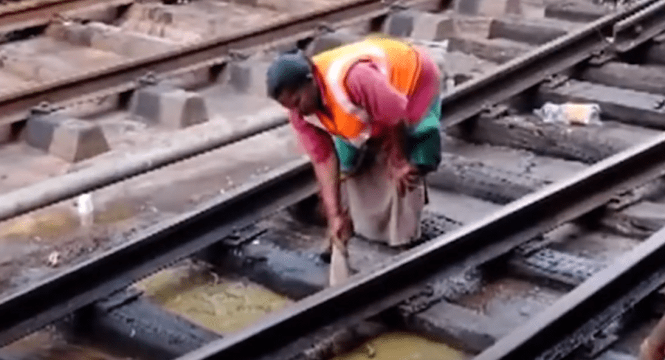 a man in an orange vest is working on train tracks