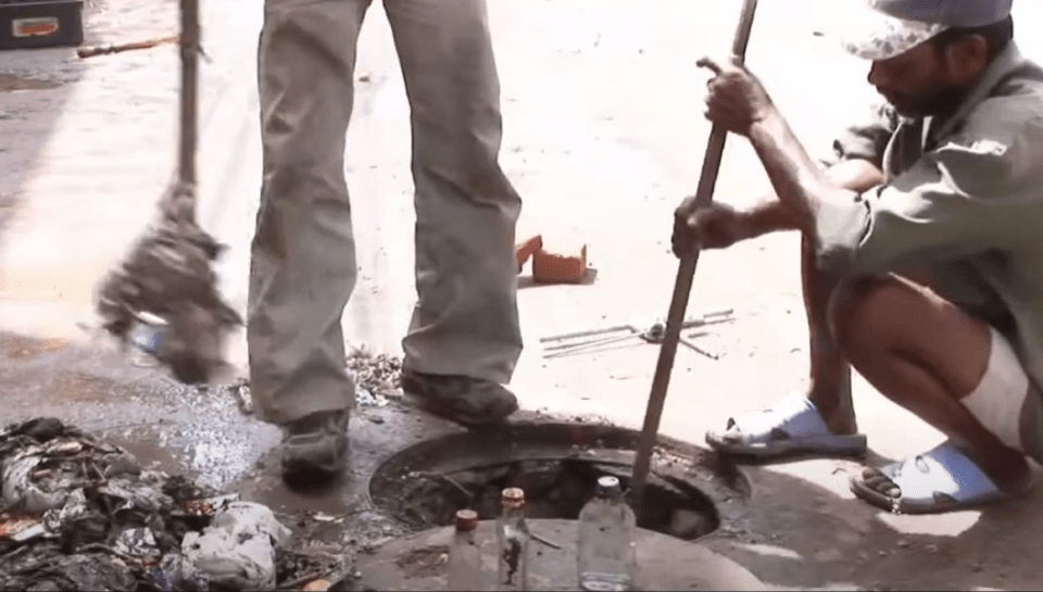 a man is kneeling down in front of a manhole cover