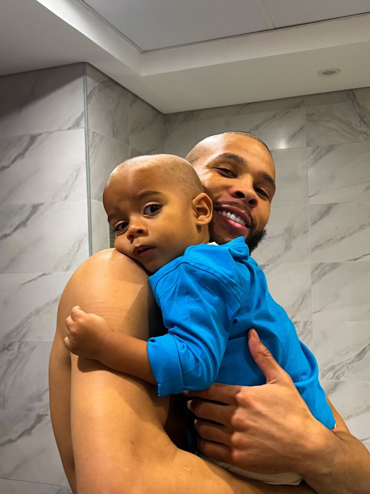 a man is holding a baby in his arms and the baby is wearing a blue shirt