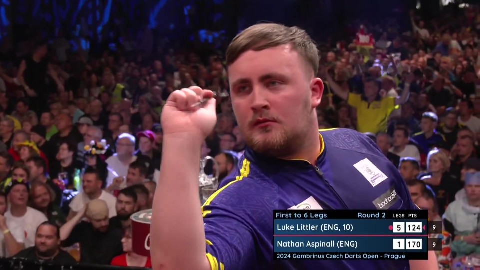 a man holds up a dart in front of a crowd while playing darts