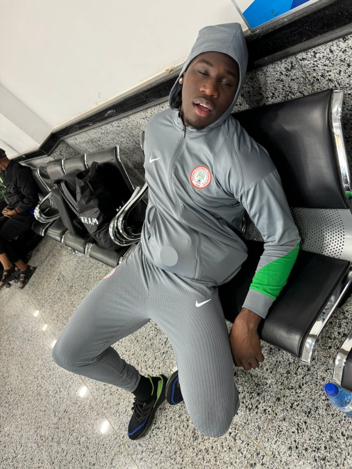 a man wearing a grey nike tracksuit is sitting on a bench