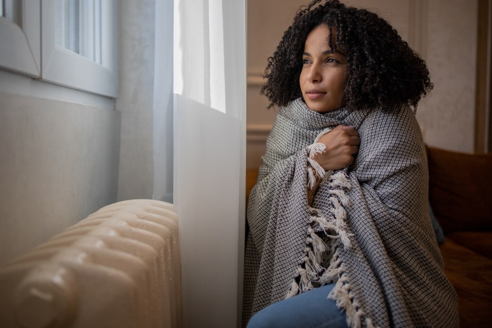 a woman wrapped in a blanket looks out a window