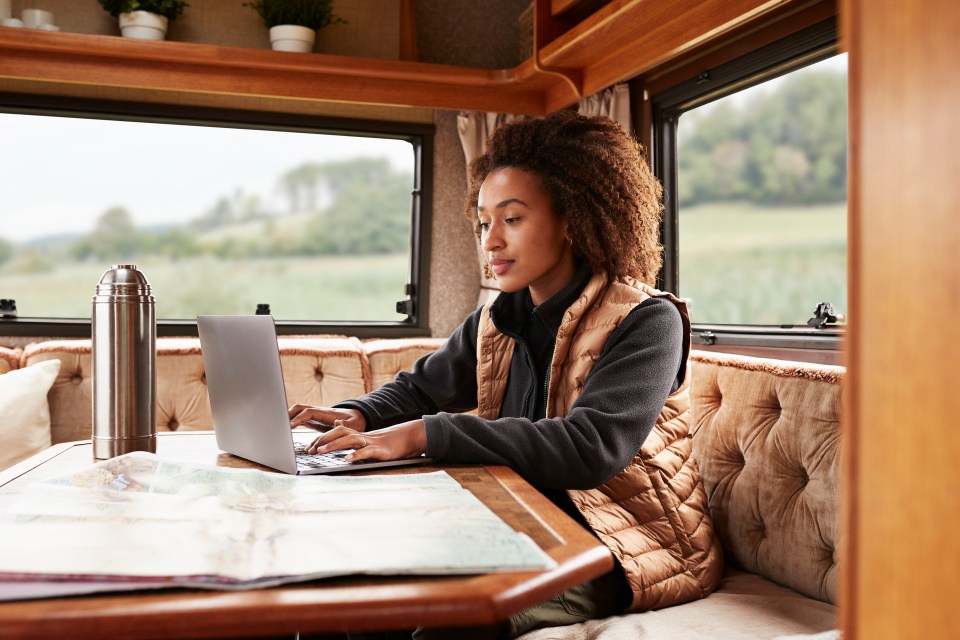 a woman sits at a table using a laptop computer