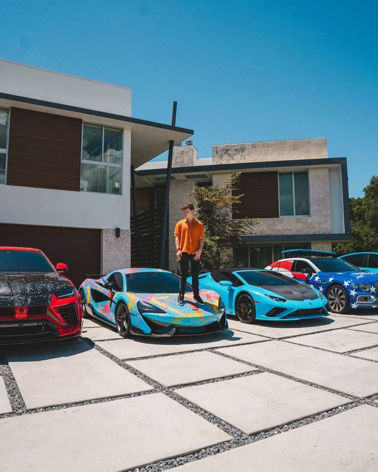 a man stands on top of a colorful sports car