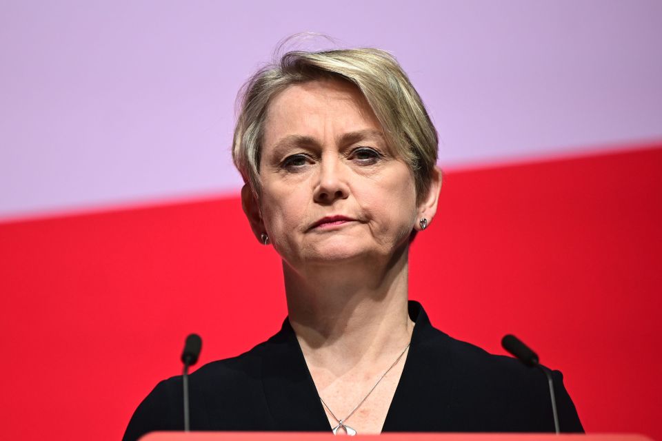 a woman stands at a podium with two microphones in front of her