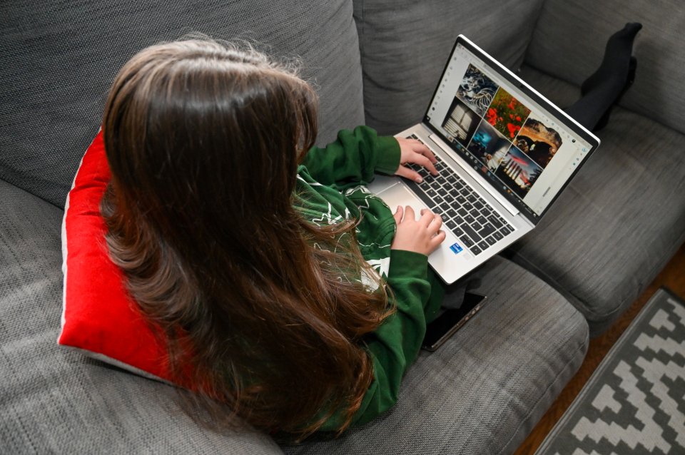 a girl is sitting on a couch using a laptop