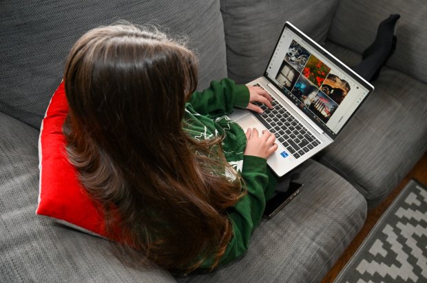 a girl is sitting on a couch using a laptop