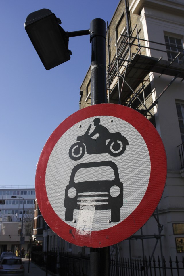 The red circle indicates 'forbidden', the car and motorcycle stand for all motorised vehicles. Commonly interpreted as 'beware of low-flying motorbikes'. Traffic sign in the centre of London, UK.