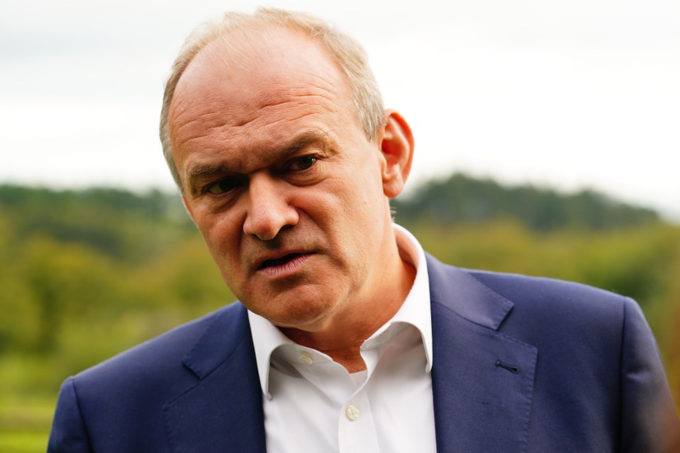 a man in a blue suit and white shirt looks at the camera