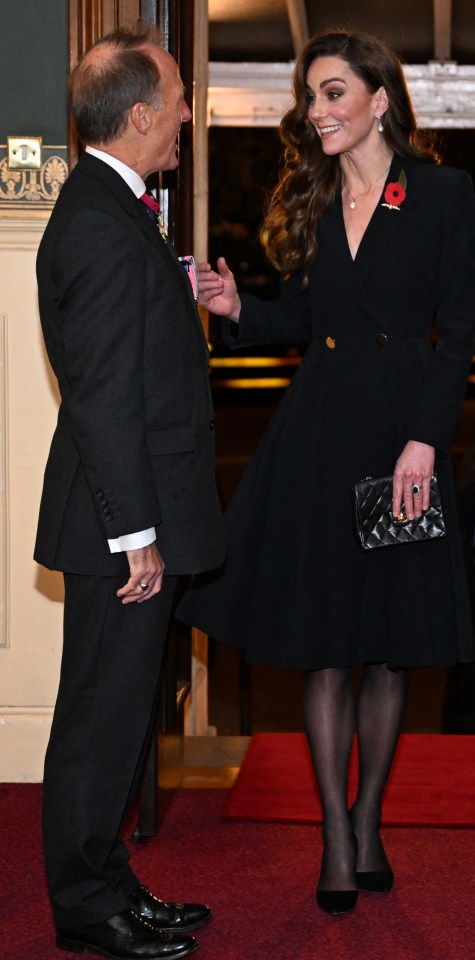 a woman in a black coat stands between two men in suits