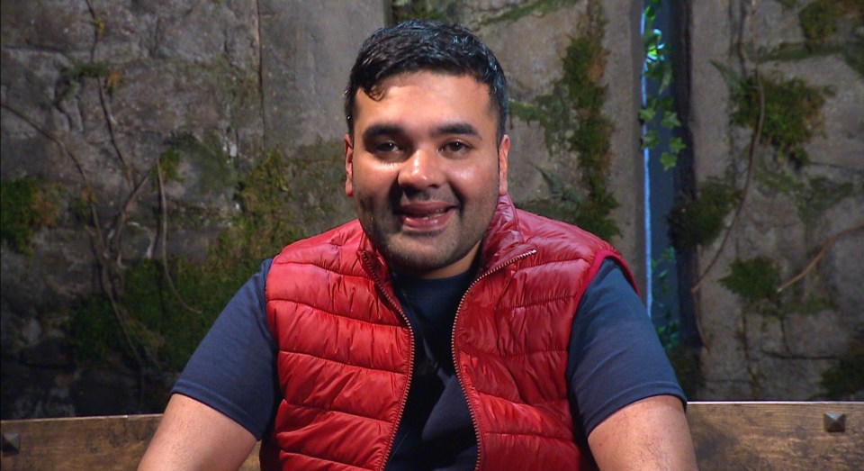 a man in a red vest sits on a wooden bench