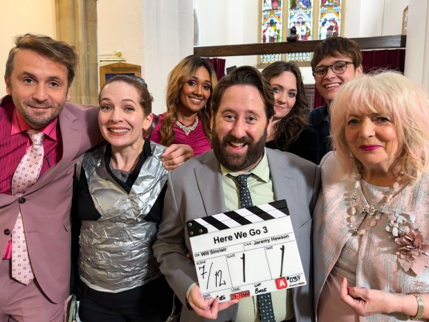 a group of people posing with a clapper board that says here we go 3