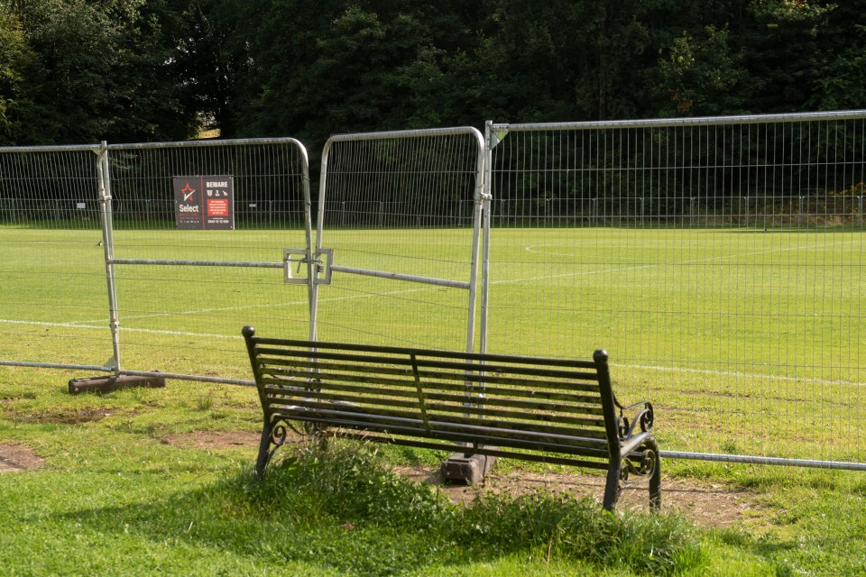 a black bench sits in front of a fence with a sign that says select