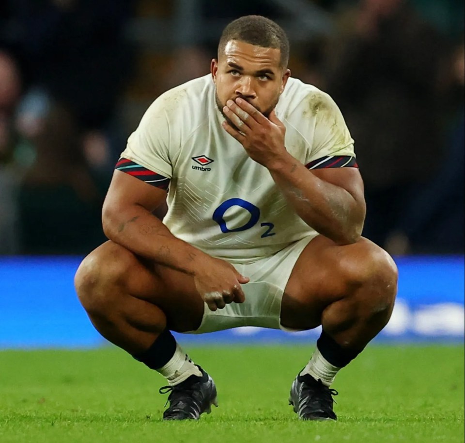 a man wearing an umbro jersey is squatting on the field