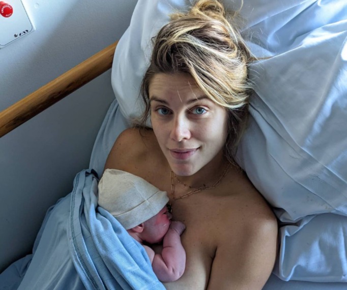 a woman is laying in a hospital bed holding a newborn baby