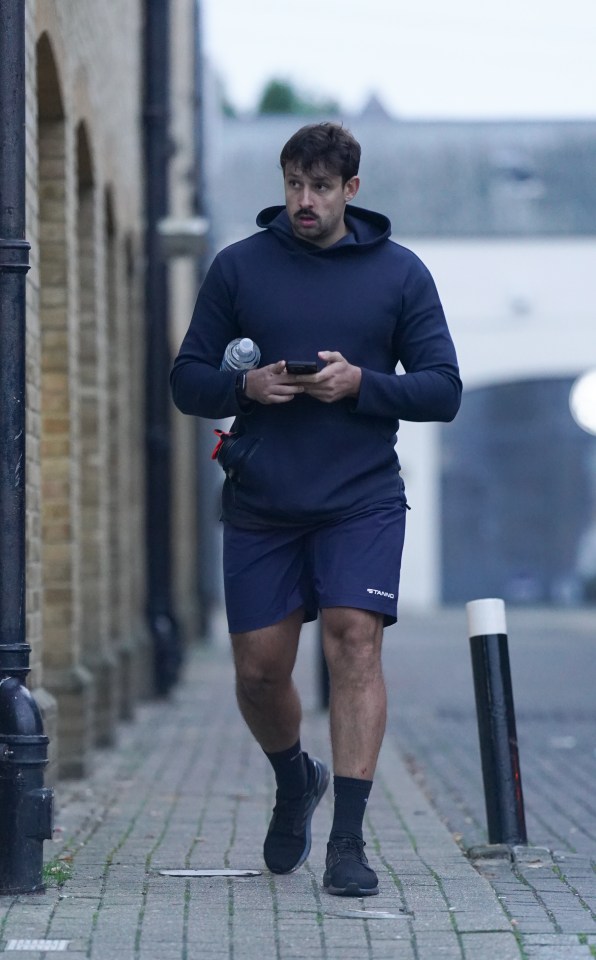 a man walking down a sidewalk with a bottle of water in his hand