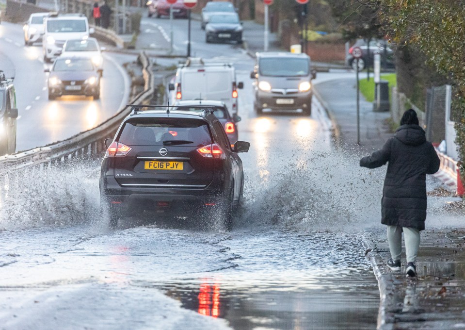 A person braves the deep surface waters on the A3 slip road near Kingston, south-west London, this morning