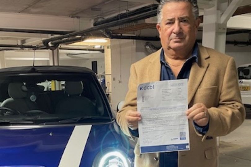 a man is holding a letter in front of a blue car