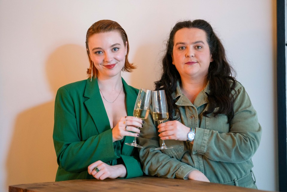 two women standing next to each other holding wine glasses