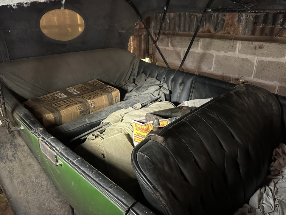 the back seat of an old car is filled with boxes including one that says ' coca cola ' on it