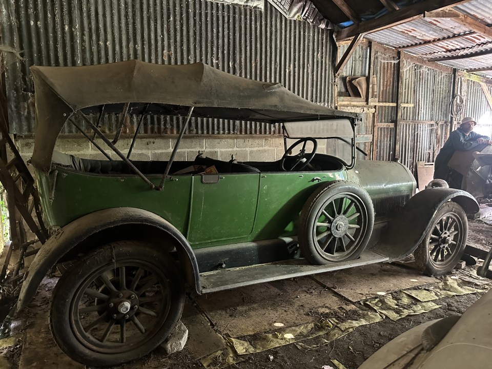 an old green car is parked in a garage