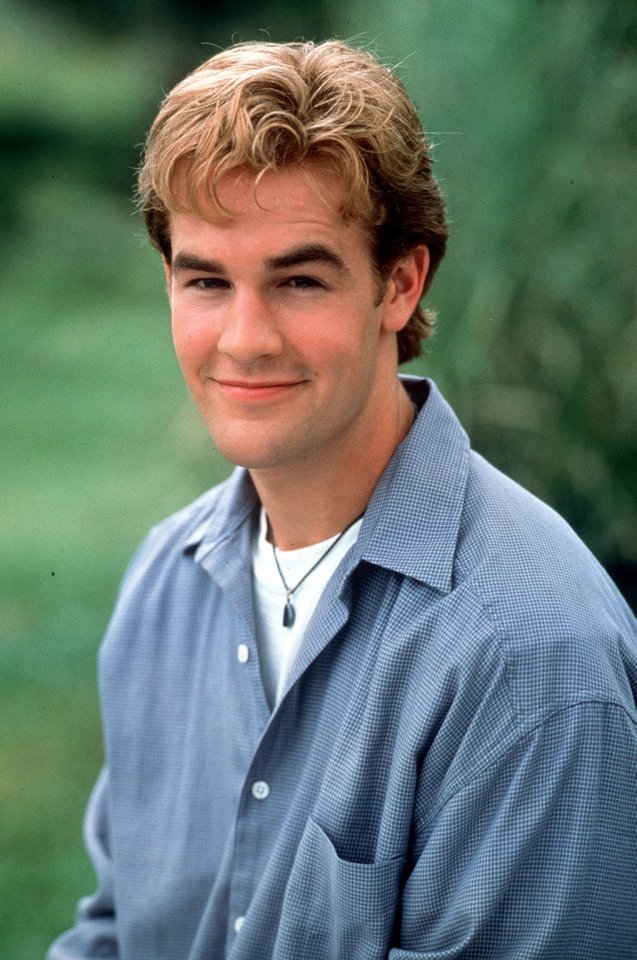 a young man wearing a blue shirt and a necklace smiles for the camera