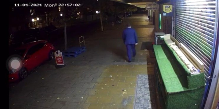 a man in a suit is standing in front of a store with a sign that says ' no parking ' on it