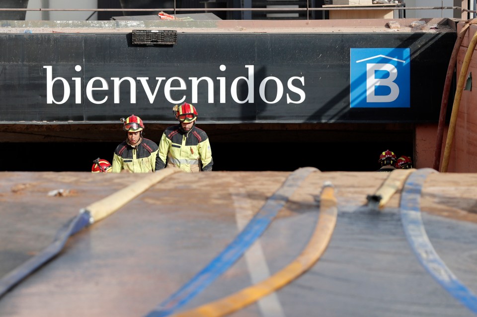 Firefighters exit a flooded underground parking garage at Bonaire mall in Valencia on Sunday