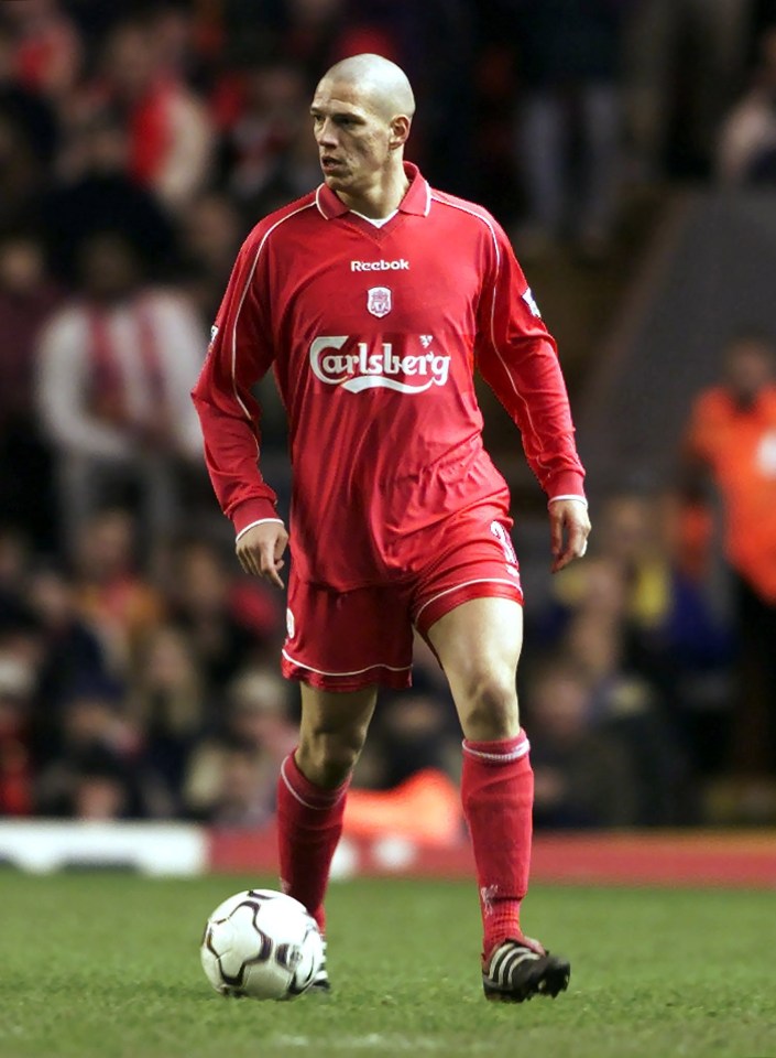 a man in a red carlsberg jersey runs with a soccer ball