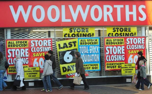 people walking in front of a store that is closing