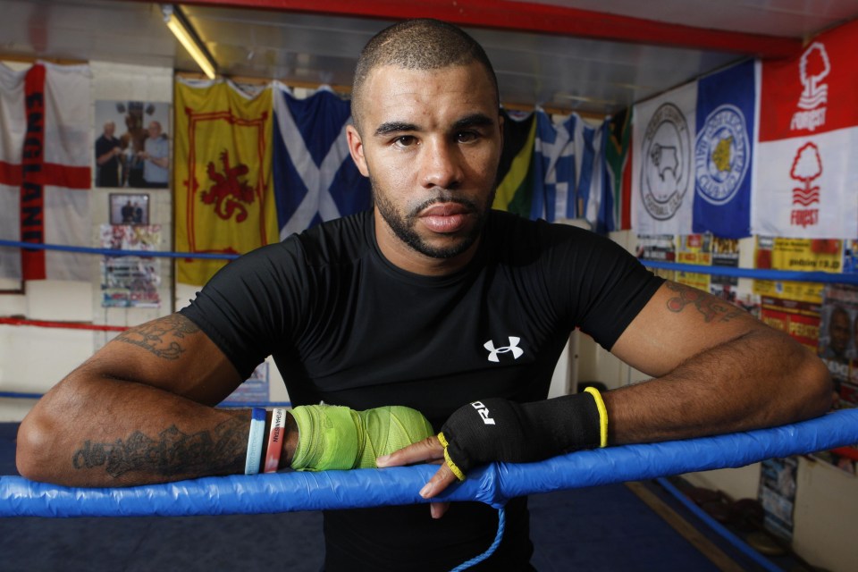 a man in an under armour shirt leans on a boxing ring