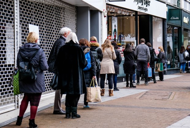 a line of people waiting outside a store called clarks