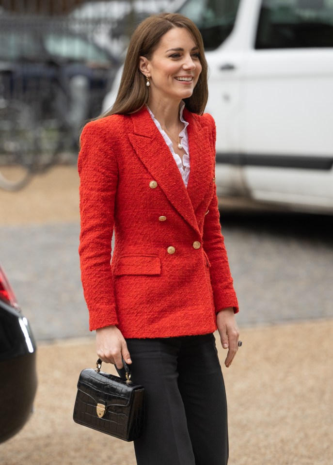 a woman is wearing a red jacket and black pants