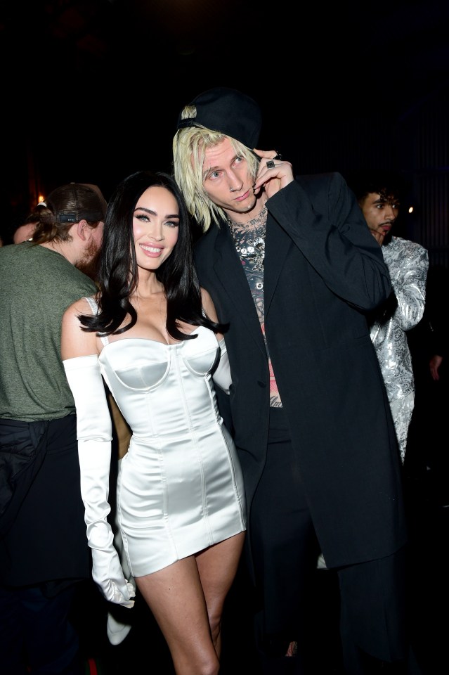 a woman in a white dress stands next to a man in a black suit