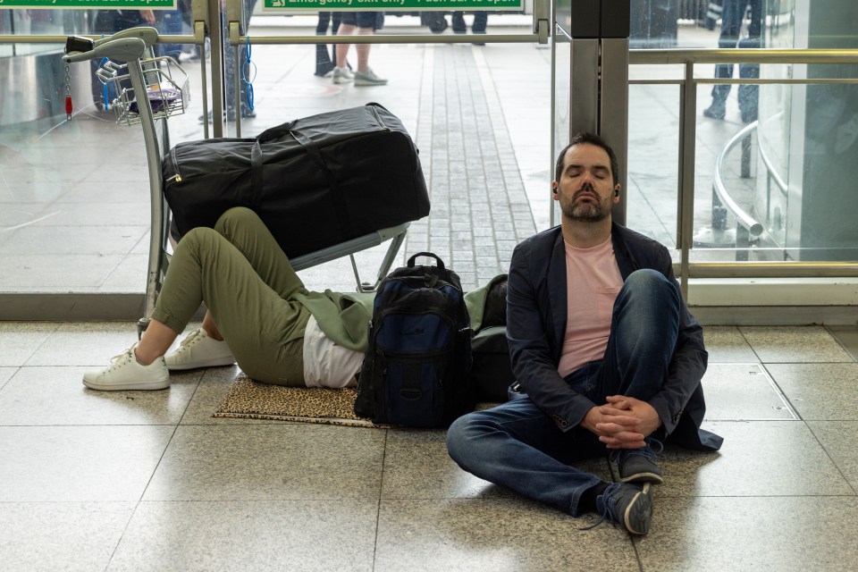 a man sits on the floor in front of a green exit sign