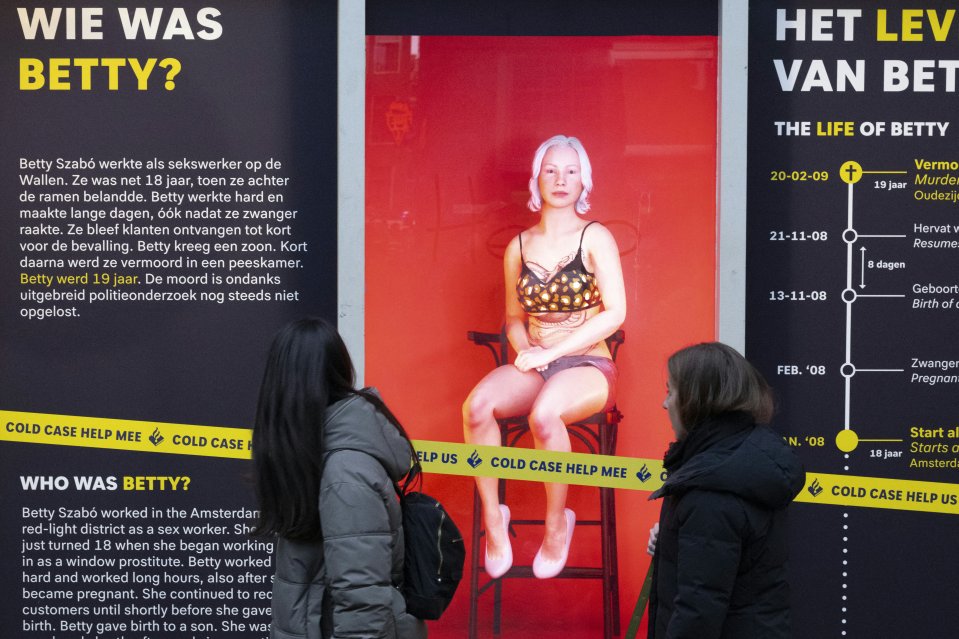 Pedestrians walk past a hologram representing murdered sex worker Betty