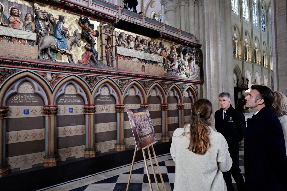 Macron looks at the artwork as he revists the refurbished cathedral